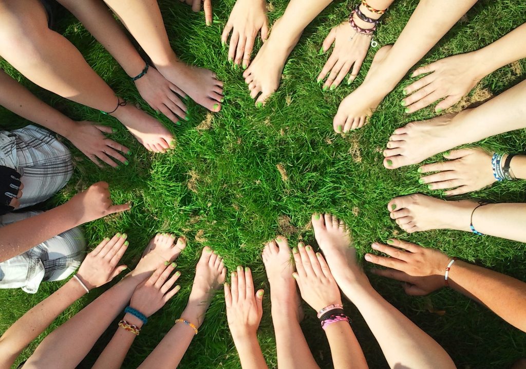 A circle of hands and feet on green grass .
